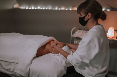  A serene spa room with soft lighting and a massage table draped in luxurious linens, setting the scene for a blissful 2-hour massage and facial treatment at Room and Pillar Spa in Kelowna, BC.